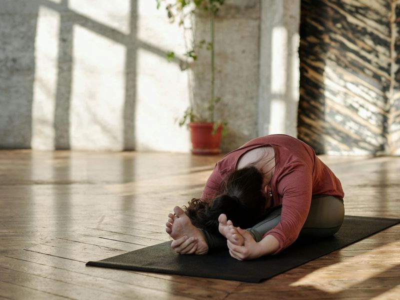 Person transitioning smoothly between two exercise poses in a sunlit room.
